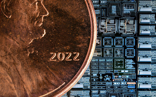A completed wafer produced for Notre Dame's Integrated Circuit Fabrication course here shown in relation to a penny. The wafer contains images related to Notre Dame to help students orient their location relative to the circuit patterns. Four sound chips can be seen on the right hand side of the photo.